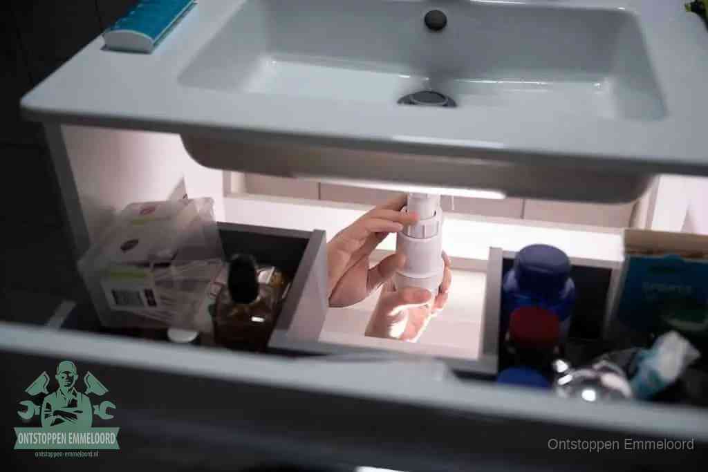 Een pompfles met zeep boven een wastafel, de heet water en afwasmiddel-methode om een vetprop in de afvoer los te maken in Emmeloord