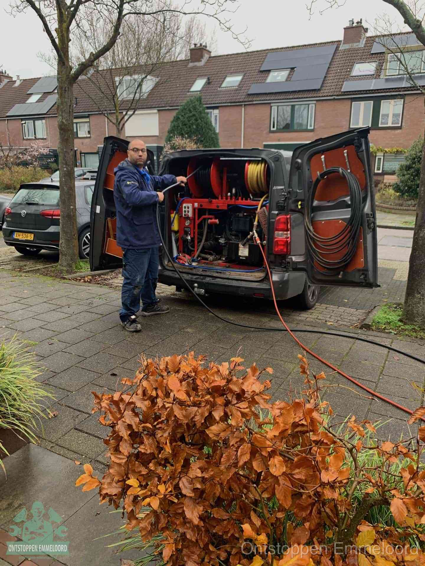 Monteur met rioolreinigingsbus levert rioolservice in de wijk in Emmeloord