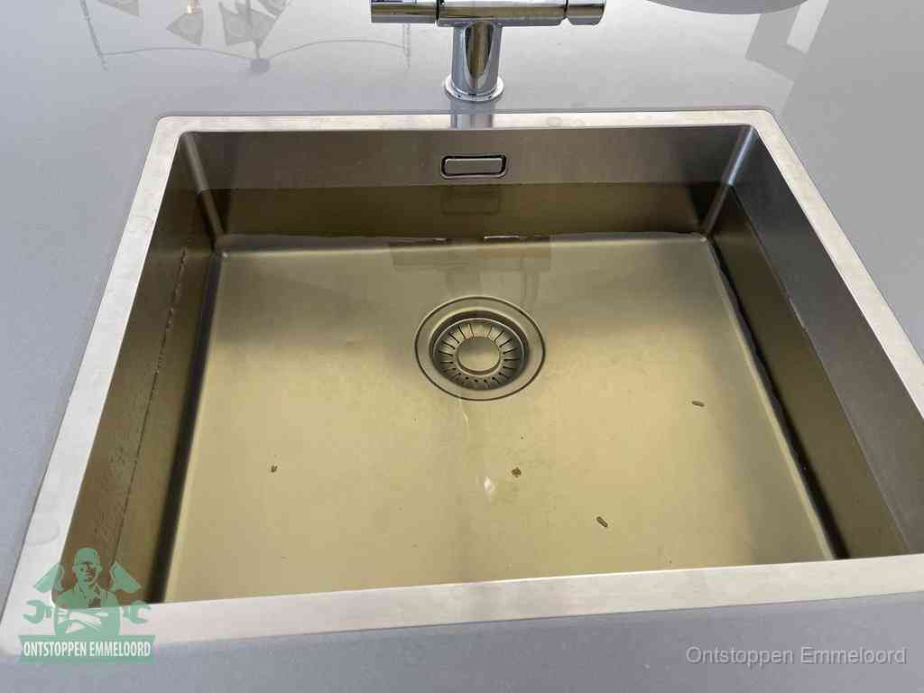 Stilstaand water in een rvs spoelbak dat niet wegloopt, een duidelijk signaal van een gootsteenverstopping in Emmeloord