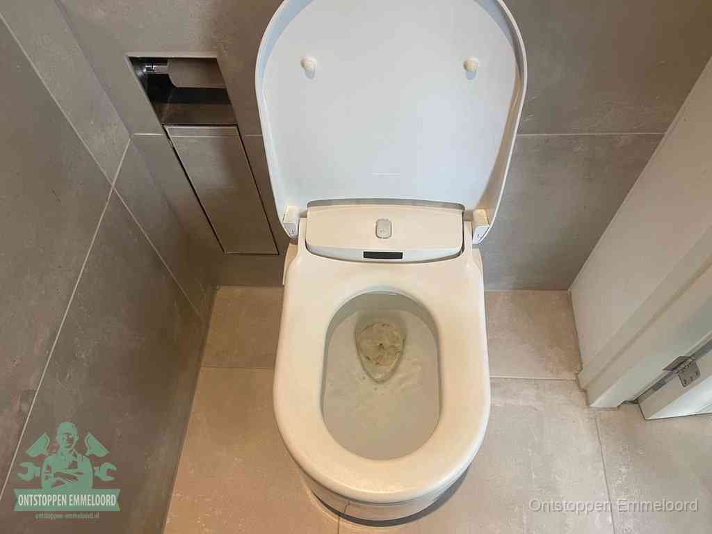 Een wit hangtoilet waarin een prop wc-papier op het water blijft drijven, een duidelijk signaal van een verstopte wc in Emmeloord