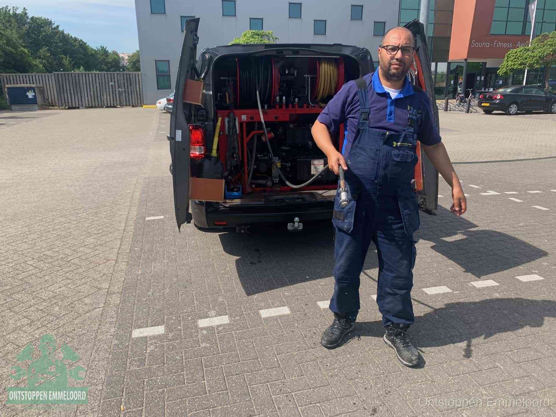 Een monteur bij zijn bestelbus met een hogedruk- en rioolreinigingsunit, klaar om de oorzaak van terugkerende wc-verstoppingen aan te pakken in Emmeloord