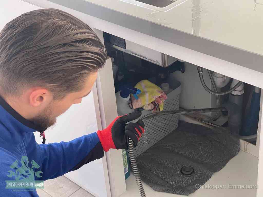 Een monteur voert een flexibele ontstoppingsveer in de afvoer om een verstopping voorbij de bocht van het toilet te bereiken in Emmeloord